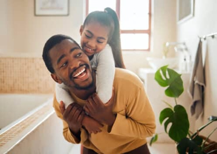 Smiling father giving daughter a piggyback ride
