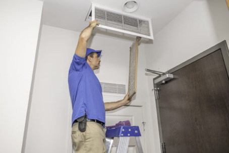 A technician changes a ceiling air filter.