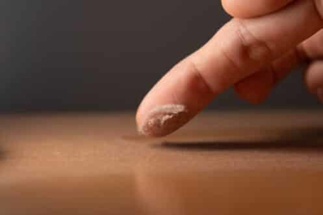 A finger touching a dusty surface