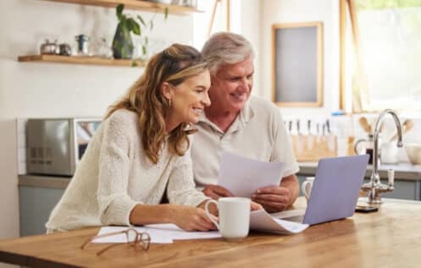 Middle-aged couple reviewing papers by a laptop